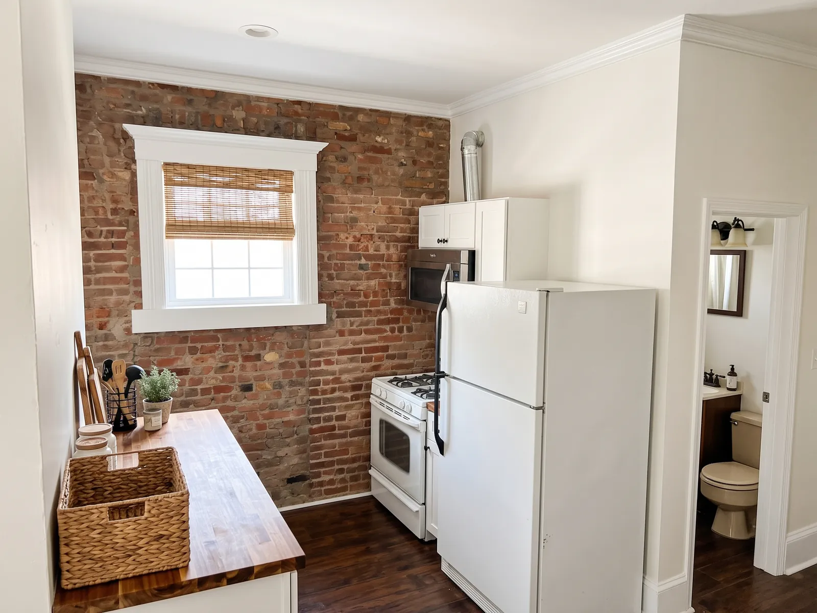AI generated modern farmhouse restyle of the same kitchen: white walls, a butcher block worktop, a bamboo blind and black wall lights. Brick wall, window, fridge, cooker and bathroom door stay in place.